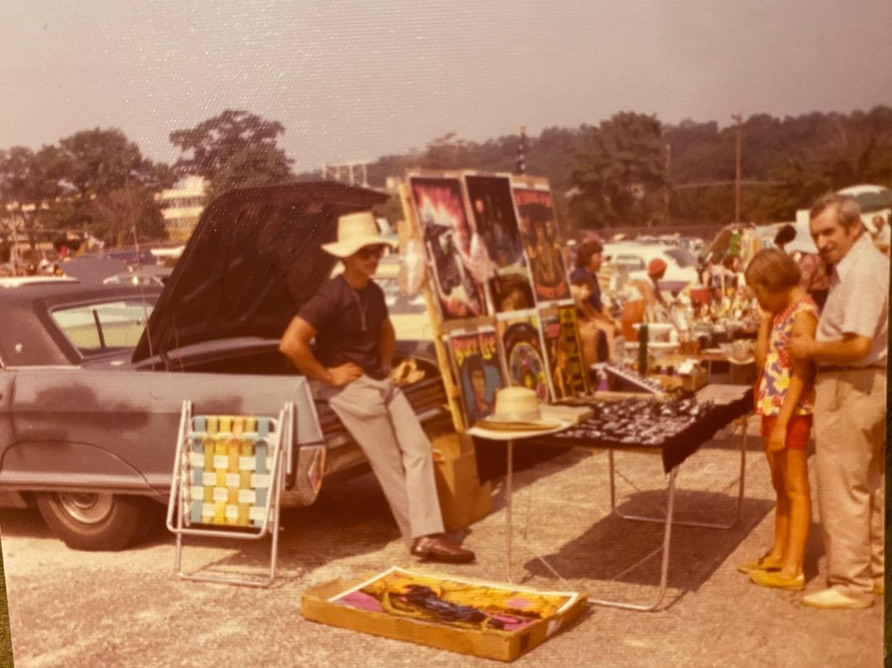 A market stall selling blacklight posters, set up beside a station wagon