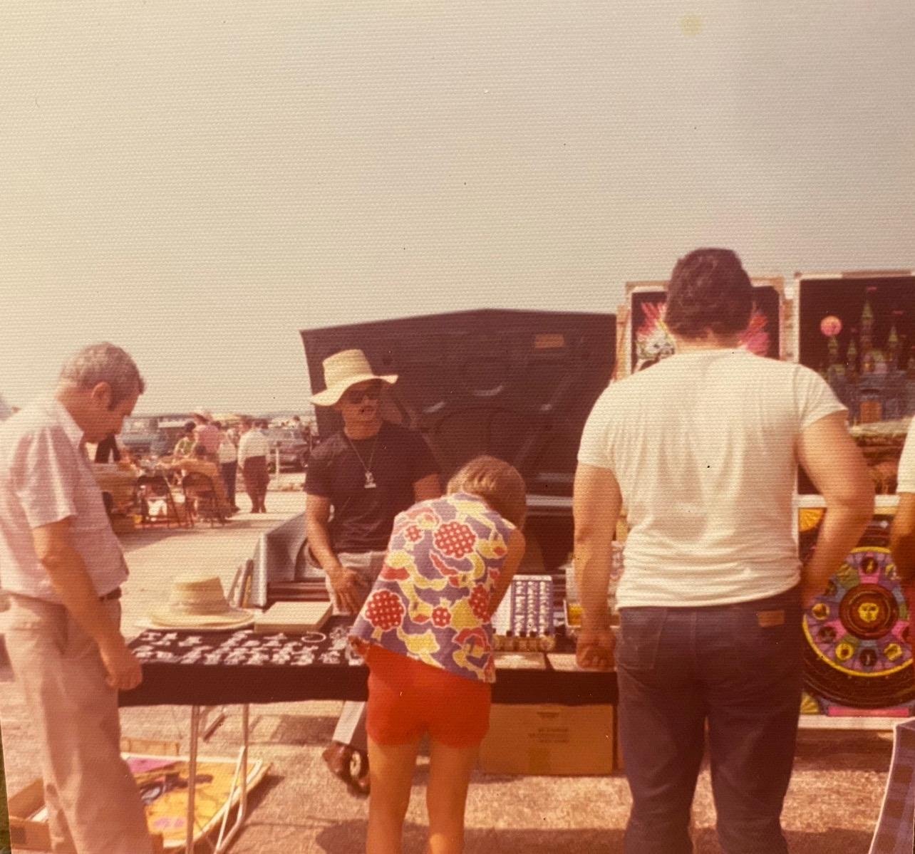 Customers browsing the market stall's jewelry and posters
